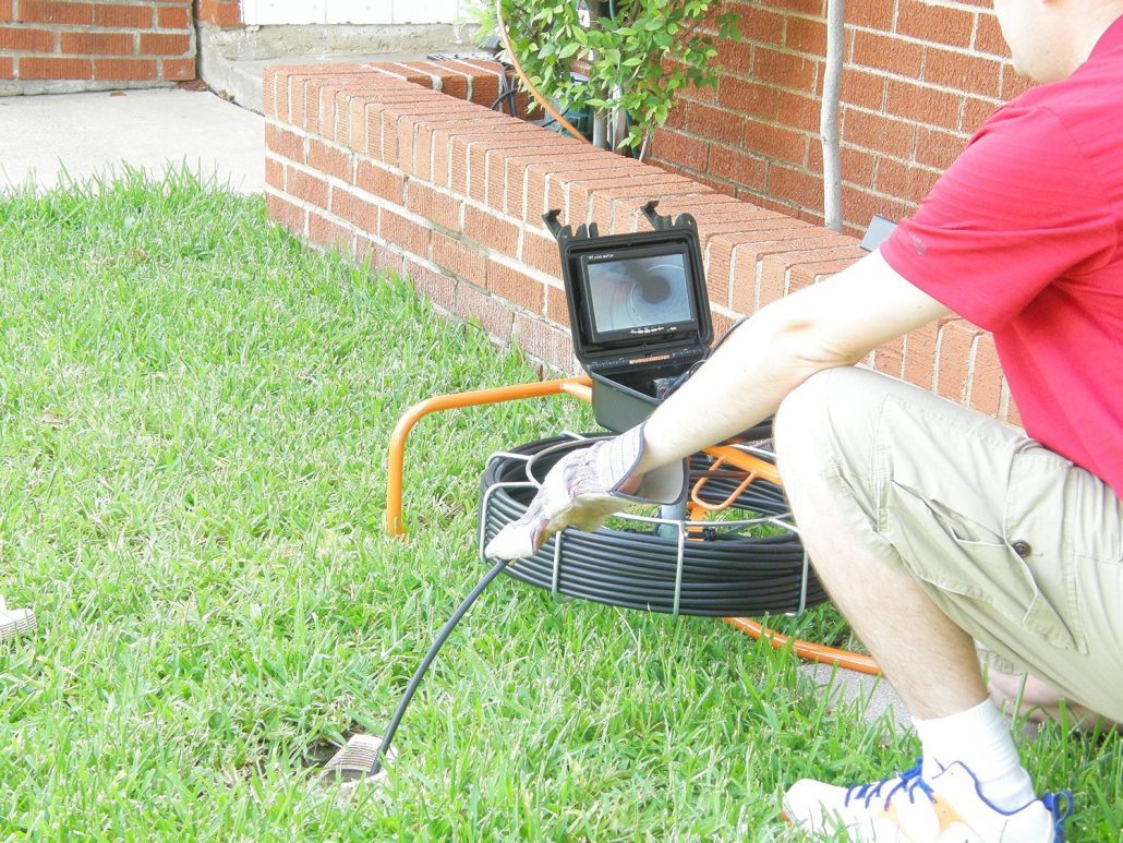 Surveillance equipment with a long wire being pushed into an outdoor drainage opening for inspection